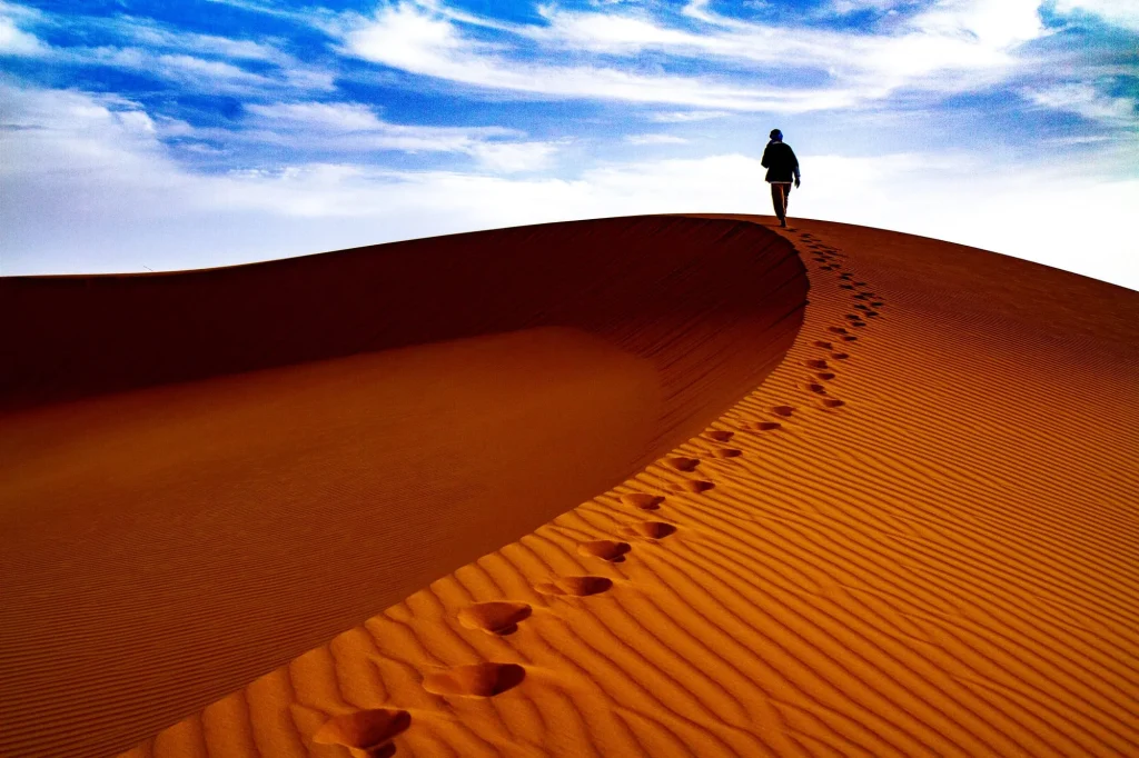Homme marchant sur la crête d'une dune dans le sahara marocain