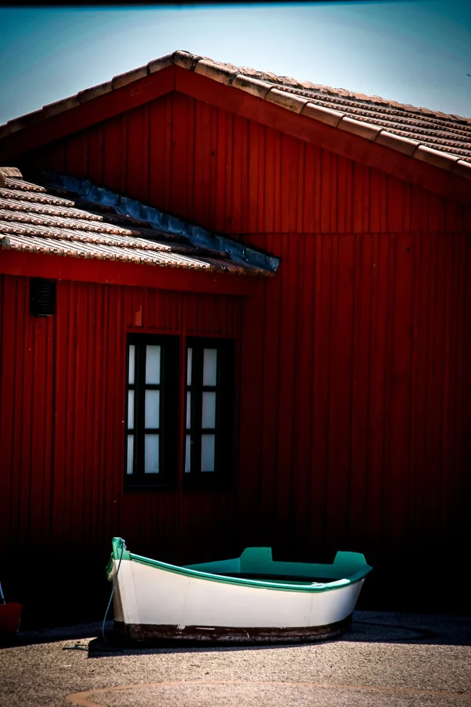 Cabane rouge en bois et barque verte, à Biganos