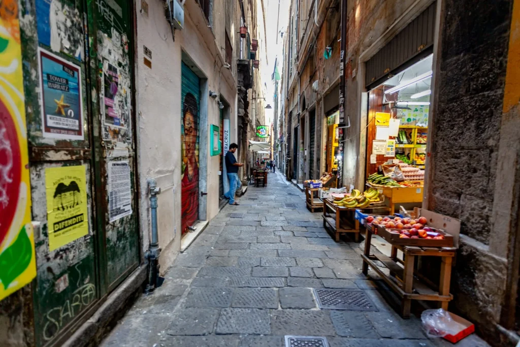 Ruelle pavée de Gênes, étals de fruits devant les boutiques