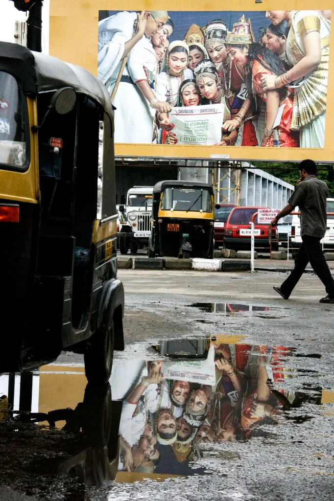 Rickshaw et affiches reflétés dans une flaque, en Inde