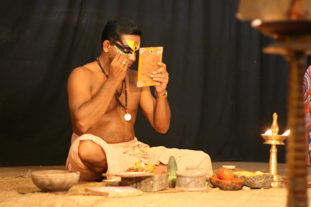 Acteur de kathakali qui se maquille devant un miroir