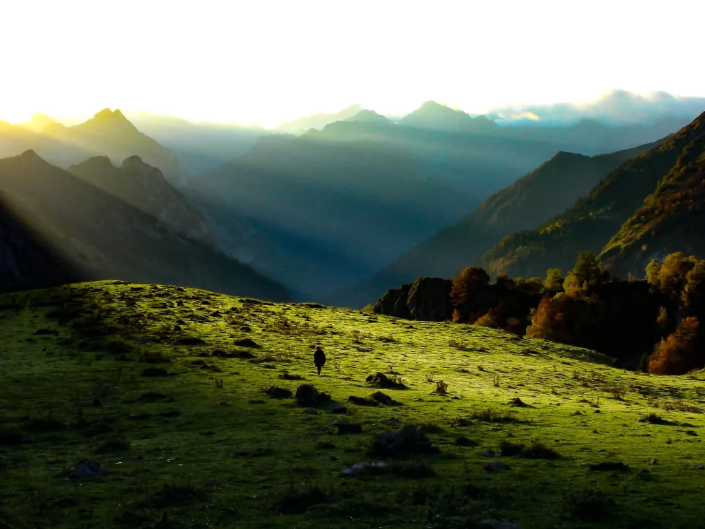 Lumière rasante sur les crêtes des Pyrénées, un marcheur dans l'herbe